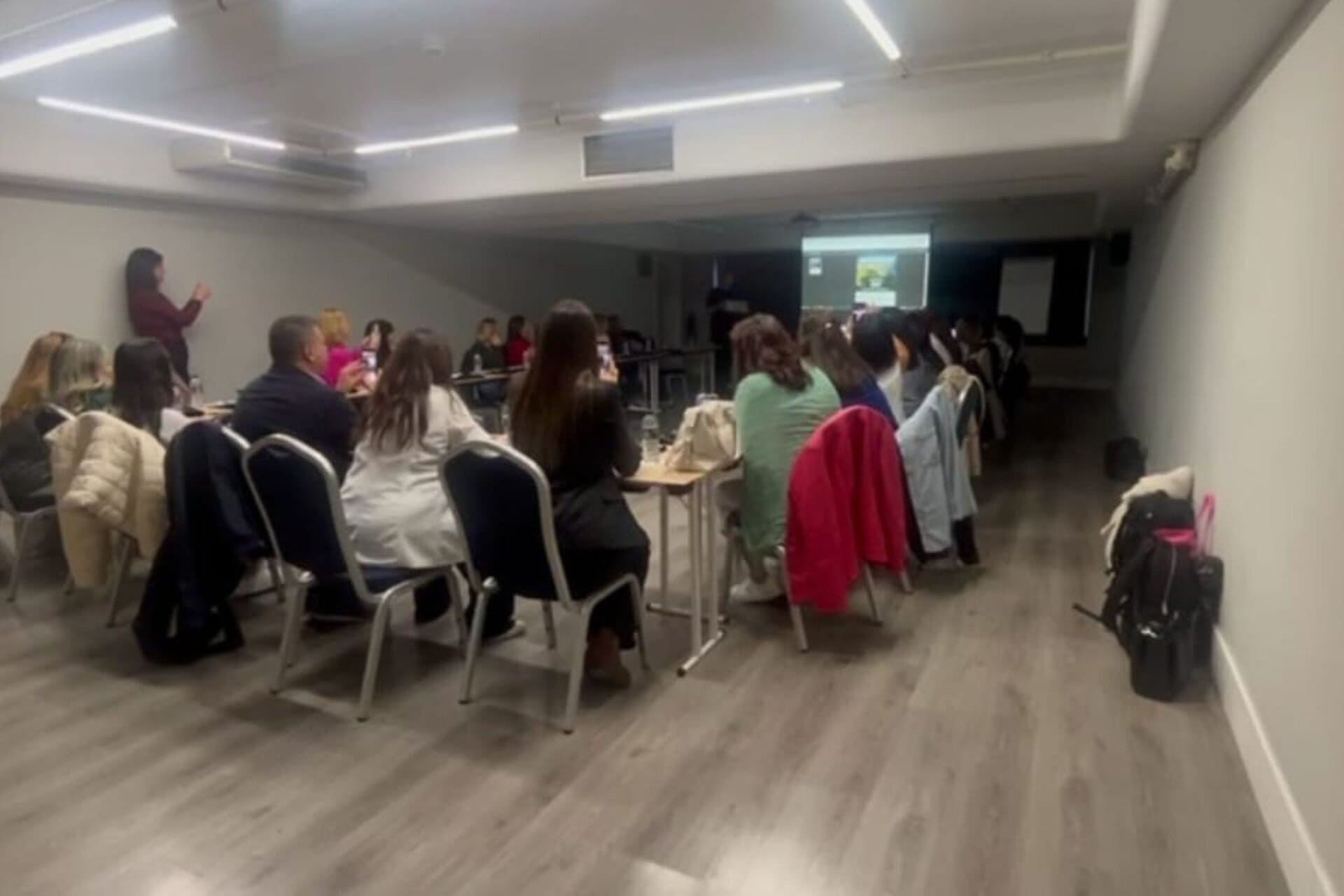 Asistentes en una sala de reuniones viendo una presentación en una pantalla.