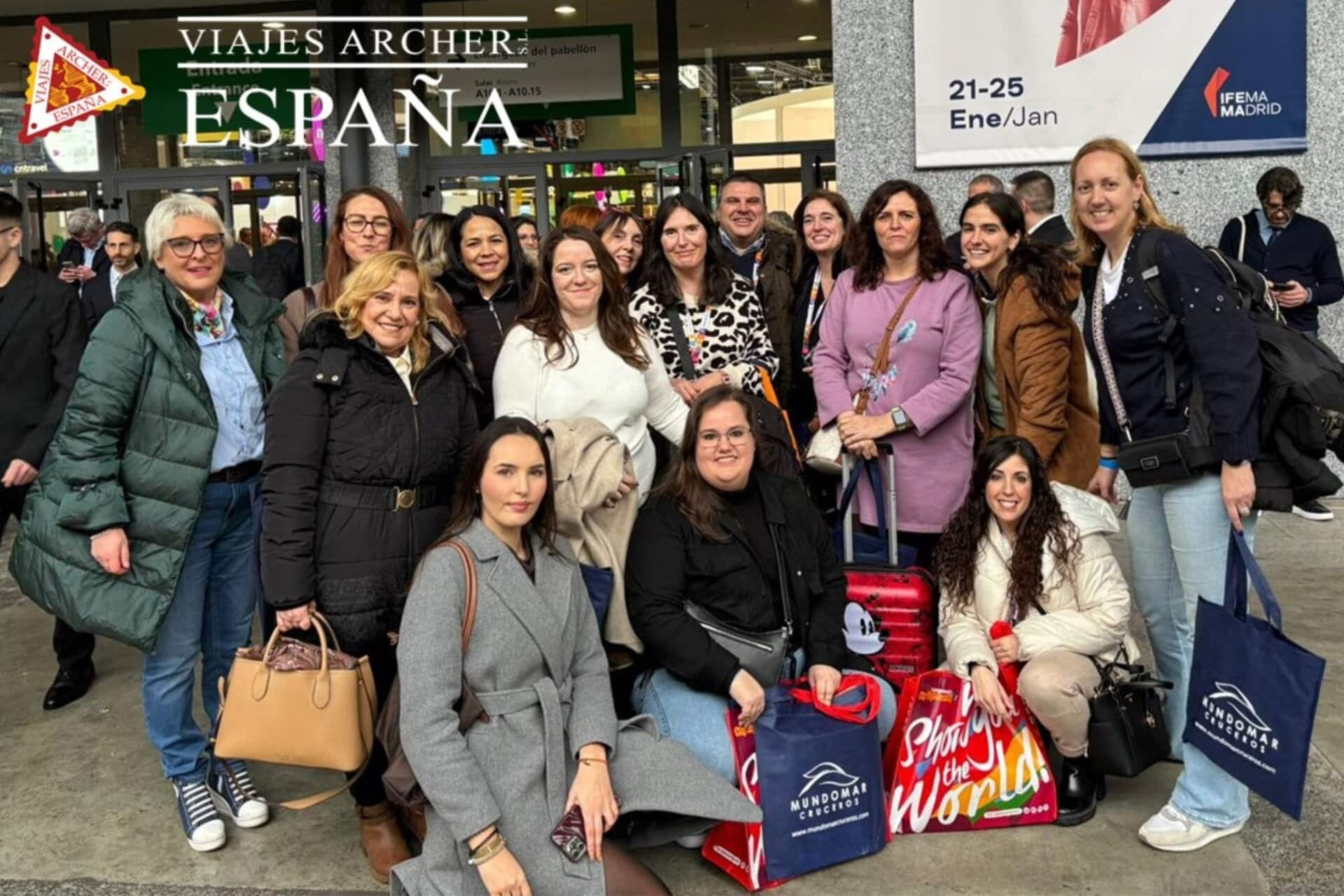 Viajeros en la entrada de un aeropuerto con maletas y bolsas, listos para su viaje a España.