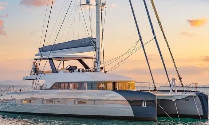 Nave de lujo en el mar al atardecer con cielo naranja y agua tranquila.