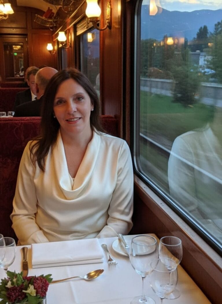 Viajera disfrutando de un viaje en tren con vista a las montañas y el paisaje natural.